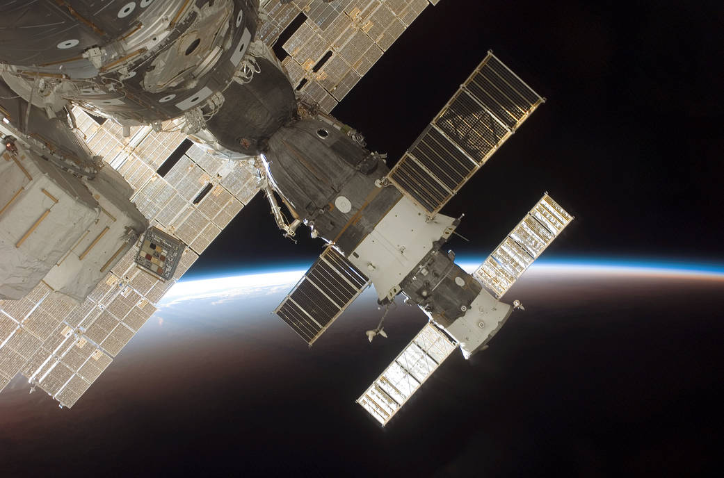 The blackness of space and Earth's horizon provide the backdrop for this image of the docked Soyuz 13 (TMA-9) (foreground) and Progress 22 resupply vehicle. The STS-116 crew protographed the Soyuz from a window on the International Space Station while Space Shuttle Discovery was docked with the station. NASA