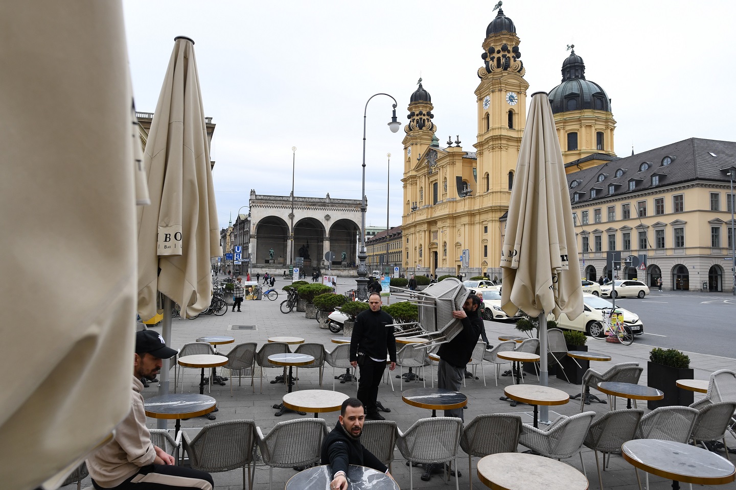 A photograph of employees at cafe Odeonsplatz removing chairs and tables from the terrace due to earlier closing hours on March 17, 2020 in Munich, Germany.