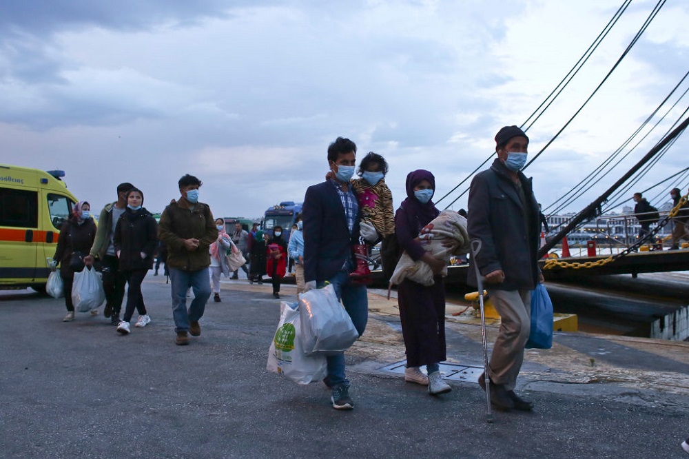 Migrants from the Moria camp in Lesbos island wearing masks to prevent the spread of the coronavirus, wait for a bus after their arrival at the port of Piraeus on May 4, 2020 in Athens, Greece. Greek authorities are moving 400 migrants, mostly families, to the mainland to help ease overcrowded conditions at the camp Moria in Lesbos island.