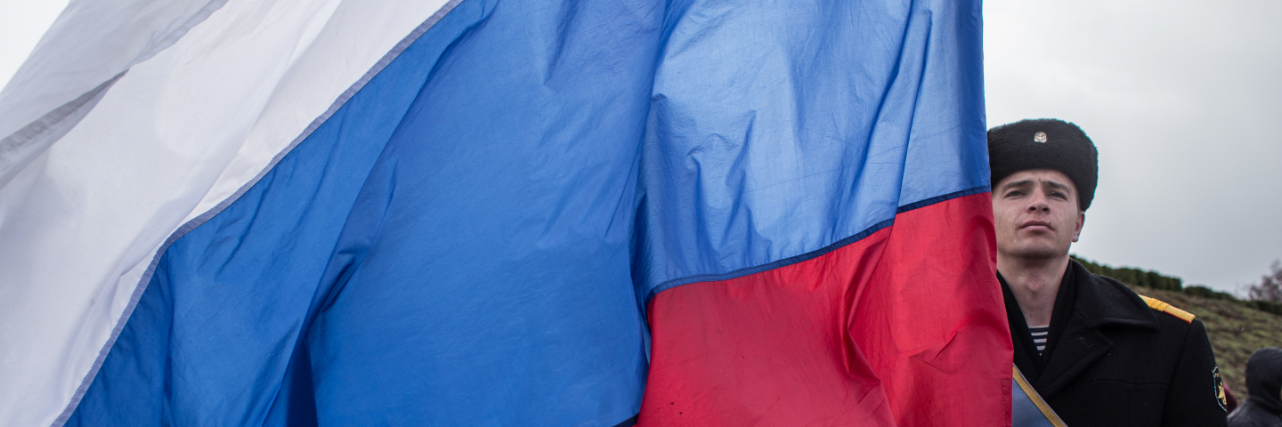 A Navy sailor holds a Russian flag as people celebrate the first anniversary of the signing of the decree on the annexation of the Crimea by the Russian Federation, on March 18, 2015 in Sevastopol, Crimea. 