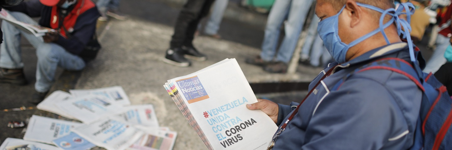 A man reads a newspaper whose headline reads "Venezuela united against the Coronavirus" outside the closed National Transport Terminal on March 17, 2020 in Caracas, Venezuela. 