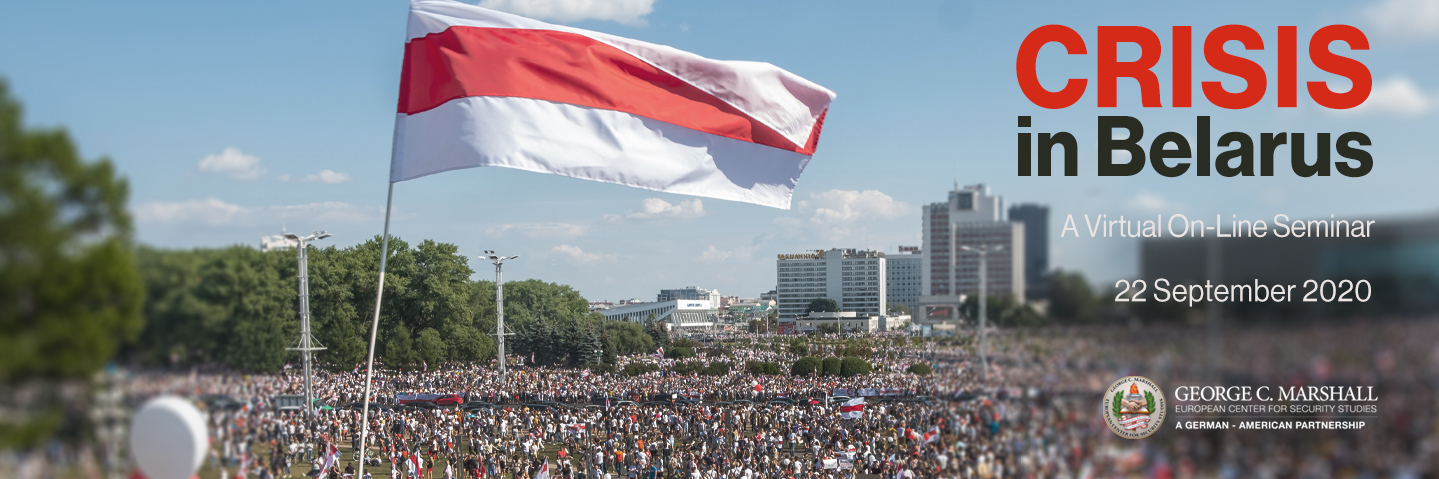 A photograph of a crowd of people with red and white balloons and flags.