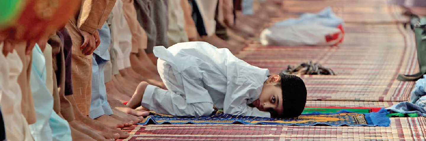 A boy kneeling for Eid al-Fitr prayers at the Jamia Masjid