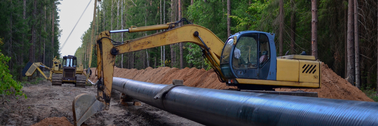 Natural gas pipeline construction work. A dug trench in the ground for the installation and installation of industrial gas and oil pipes. Crawler crane bulldozer with side boom or pipelaye
