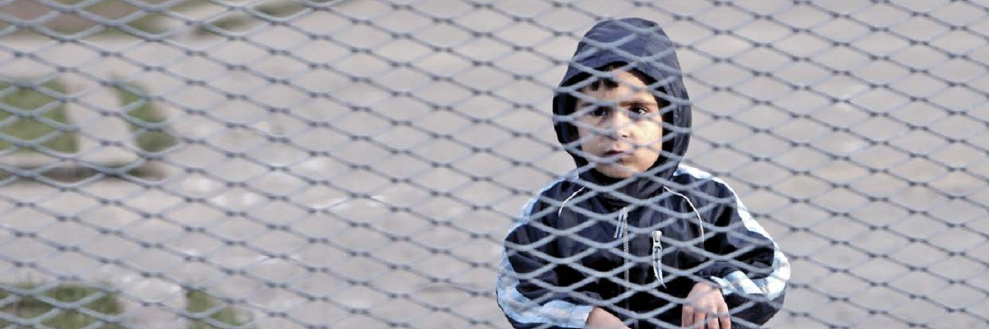 Child on bike behind fence