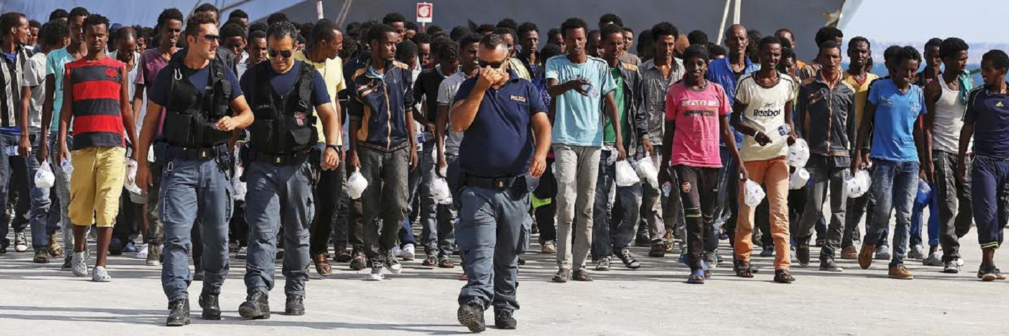 police escorting refugees in front of Naval ship