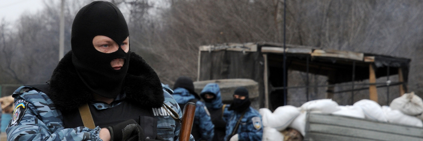 Armed masked men who call themselves members of Ukraine's disbanded elite Berkut riot police force stand at their checkpoint under a Russian flag on a highway that connect Black Sea Crimea peninsula to mainland Ukraine near the city of Armyansk, on February 28, 2014.