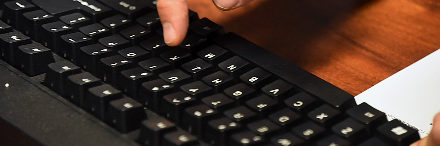 Finger reaching out to type on computer keyboard.