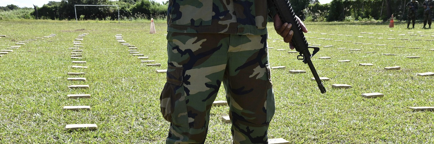 Feet and weapon of police, with custody packages containing 406 kg of marijuana and 20 kg of cocaine seized in Yacuiba, Bolivia, on the border with Argentina and Paraguay.