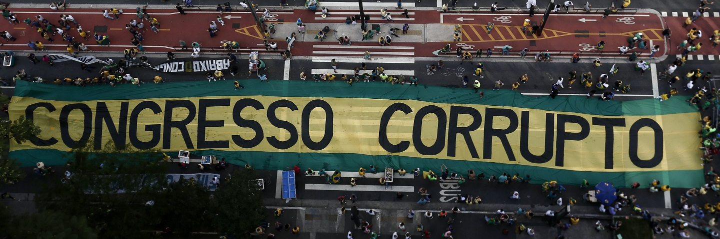Overhead view of large sign that says "Congresso Corrupto" as demonstrators protest along Paulista Avenue in Sao Paulo, Brazil.