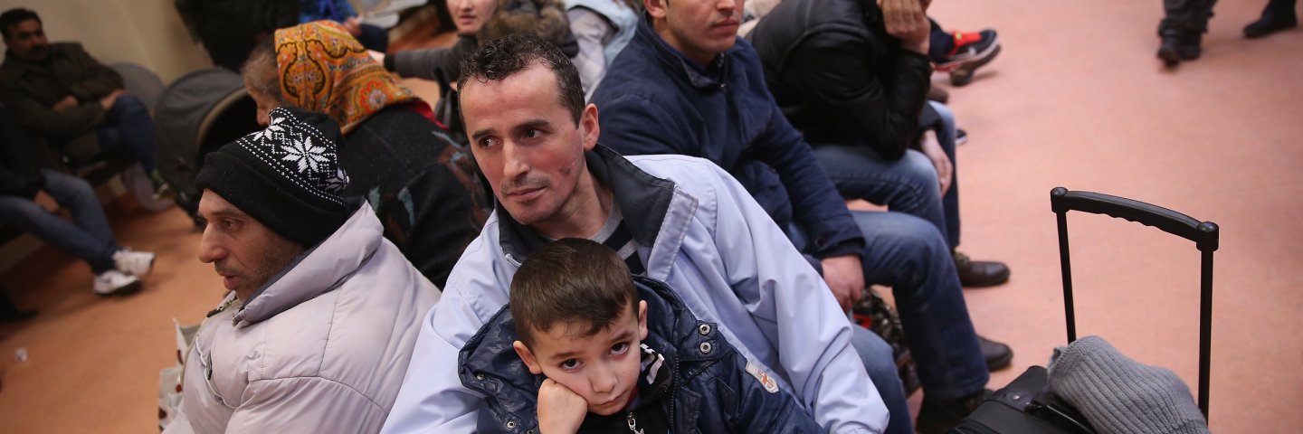 Besnek, a migrant from Albania, holds his son Enek, 6, as he and others wait to register at the Central Registration Office for Asylum Seekers (Zentrale Aufnahmestelle fuer Fluechtlinge, or ZAA) of the State Office for Health and Social Services (Landesamt fuer Gesundheit und Soziales, or LAGeSo), which is the registration office for refugees and migrants arriving in Berlin who are seeking asylum in Germany, on March 11, 2015 in Berlin, Germany.