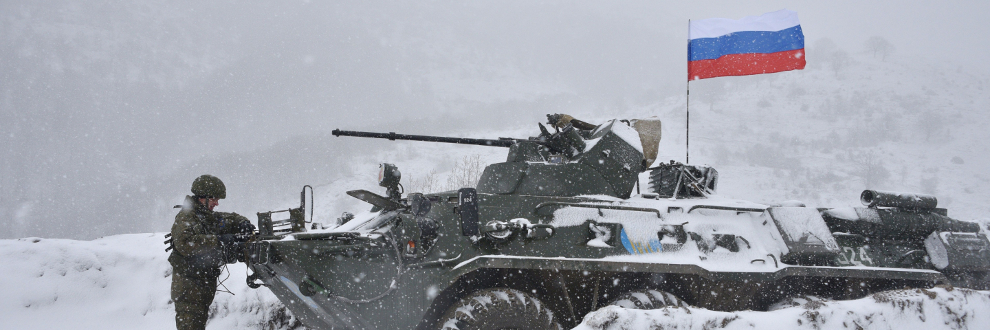 A Russian soldier of the peacekeeping force stand next to an Armored Personnel Carrier (APC) guard a checkpoint on the road to Lachin outside the town of Stepanakert on November 29, 2020, after six weeks of fighting between Armenia and Azerbaijan over the disputed Nagorno-Karabakh region.