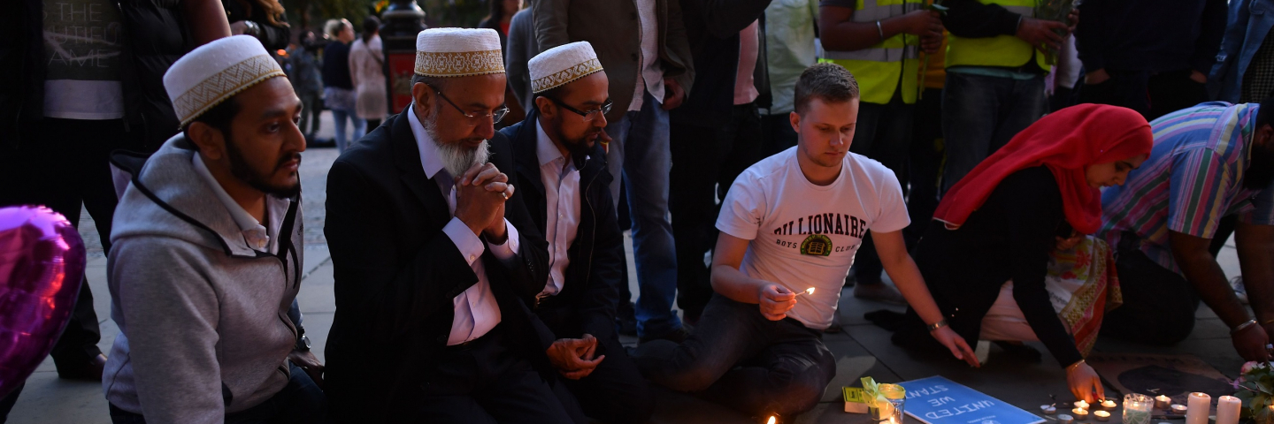People pray and light candles set up in front of floral tributes in Albert Square in Manchester, northwest England on May 23, 2017, in solidarity with those killed and injured in the May 22 terror attack at the Ariana Grande concert at the Manchester Arena.