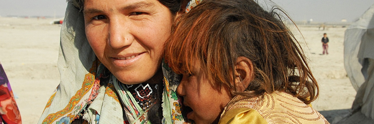 Mother and child gather to receive rice at a refugee camp in the outskirts of Kabul, Afghanistan.