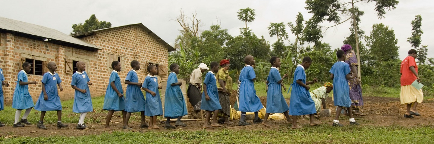 Ugandan school girls in uniform walking outside.