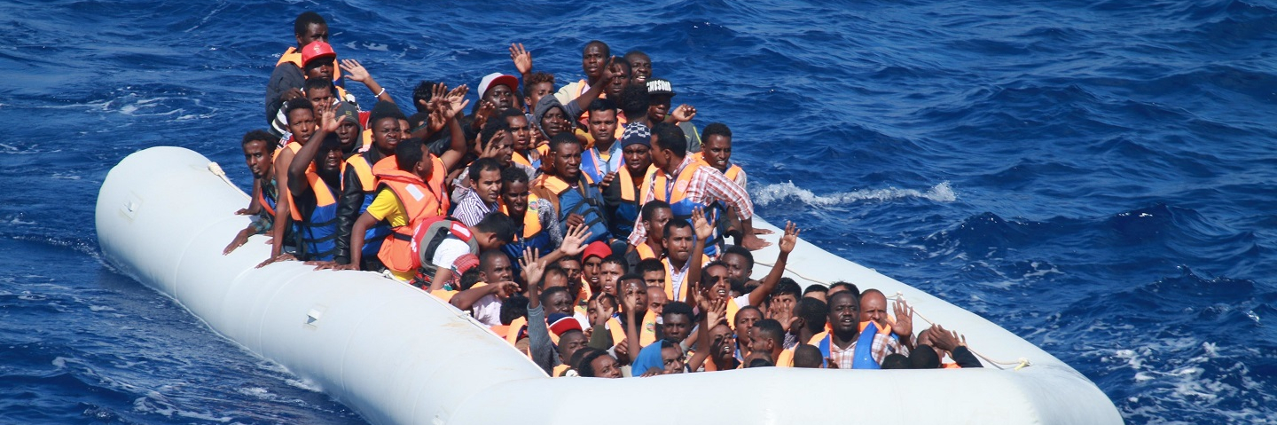 Migrants aboard an inflatable vessel approach the guided-missile destroyer USS Carney.