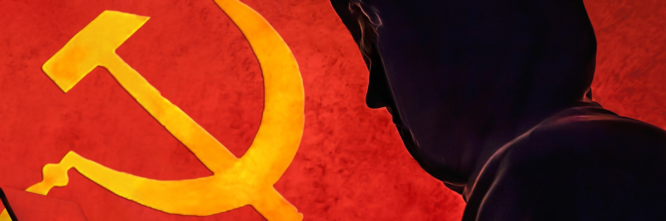 A profile silhouette of adult Russian man hacker holding his computer with the Russian flag behind him.