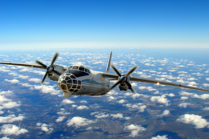 A Ukrainian An-30B aircraft flying over clouds.
