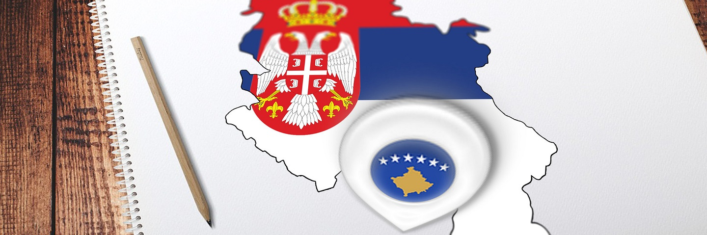 Photo of drawing book with pencil, showing map of Serbia and Kosovo with their flags on top.
