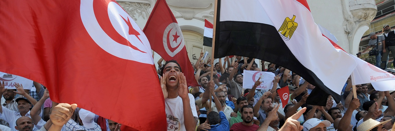 Tunisian supporters of the Islamist Ennahda ruling party hold up their national flag and Egypt's flag as they shout slogans during a protest.