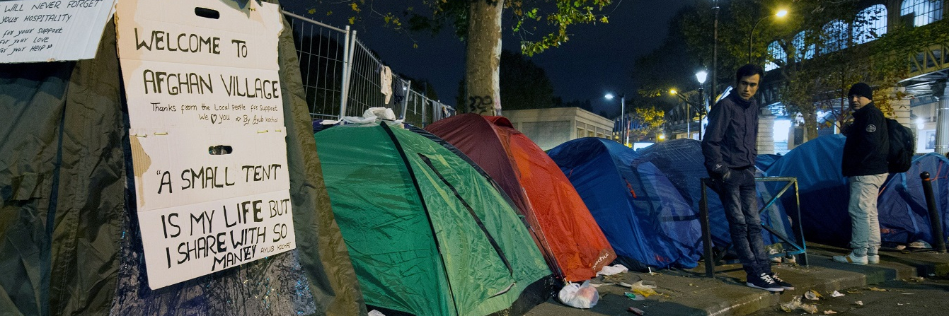 Migrants, mostly from Afghanistan, stand next to tents during an evacuation of a makeshift camp near Stalingrad metro station in Paris on November 4, 2016, one of several camps sprouting up around the French capital.