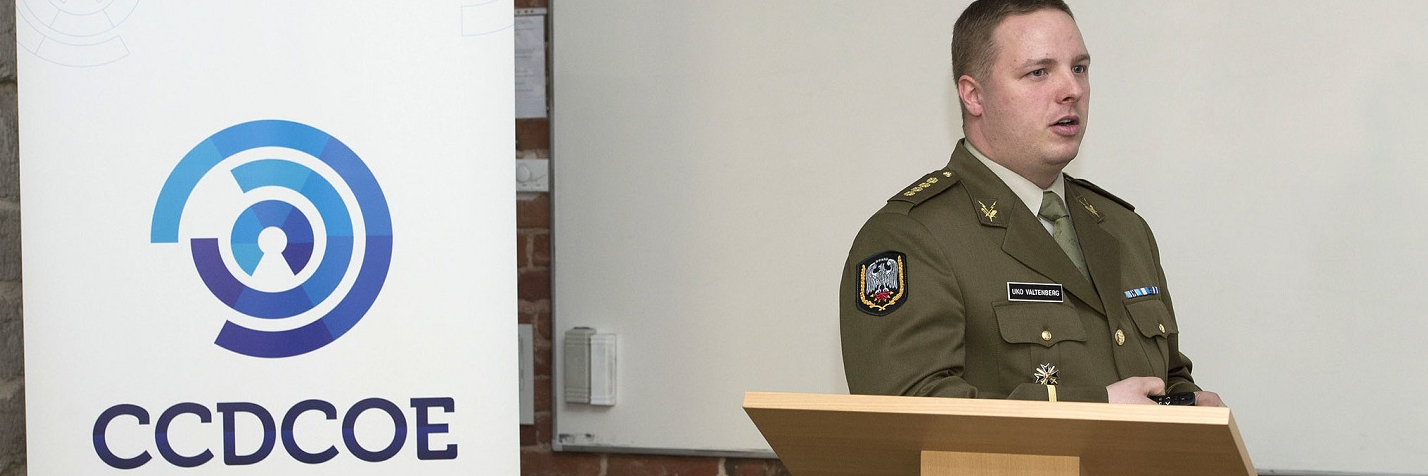 Capt Uko Valtenberg, Chief of Cyber Range, stands at the podium to deliver a briefing when The North Atlantic Council visits the NATO Cooperative Cyber Defence Centre of Excellence in Estonia.