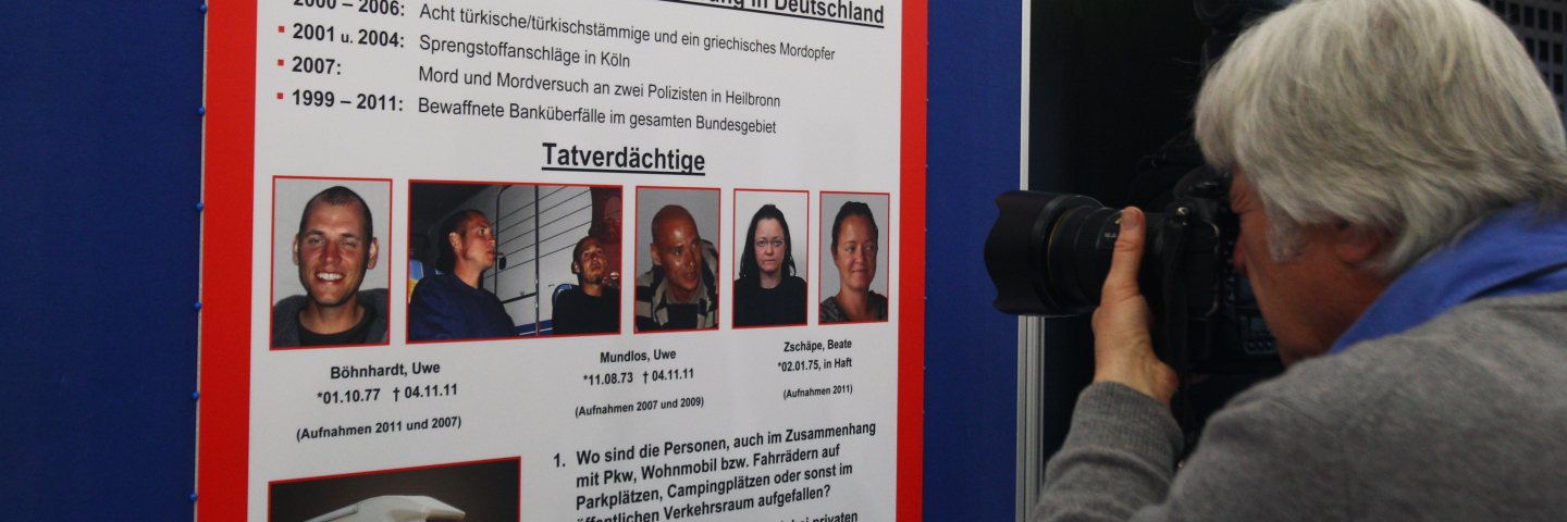 A photographer takes a picture of a wanted poster