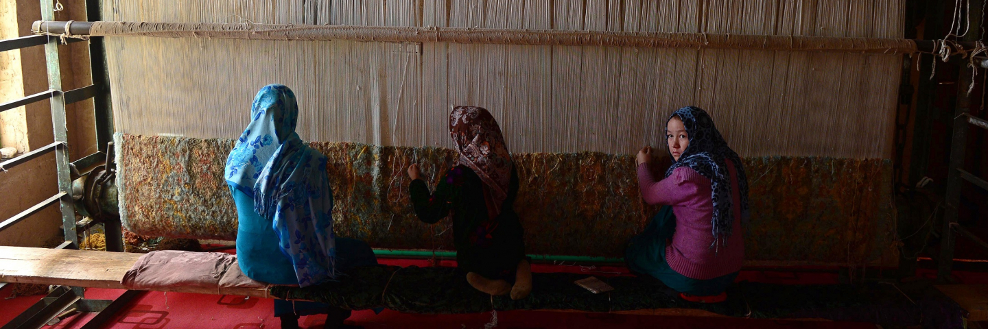 In this photograph taken on December 17, 2014 young Afghan girls weave a carpet at a carpet manufacturer in Herat. Some 42,500 women and their families are involved in the project which aims to provide a means of subsistence and potentially lead to international market access for silk producers in the country.