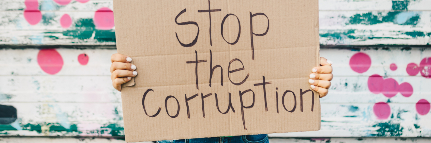 Young woman holding a poster against corruption.