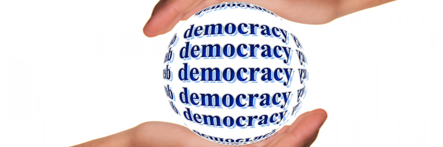 Two hands holding a ball that says Democracy