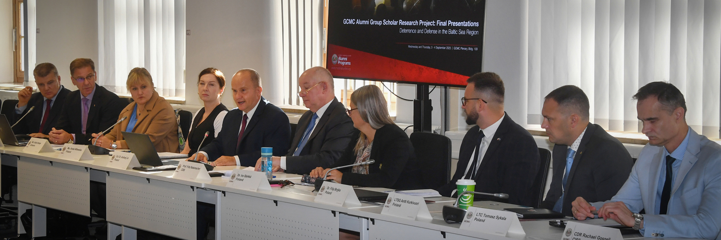 Marshall Center faculty and alumni scholars seated at a conference table during the Alumni Scholar Group Project final presentations on deterrence and defense in the Baltic Sea region. A presentation screen is visible in the background.