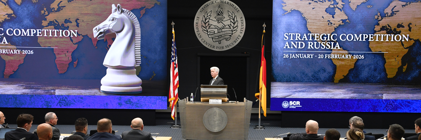 Man speaks in front of a plenary crowd.