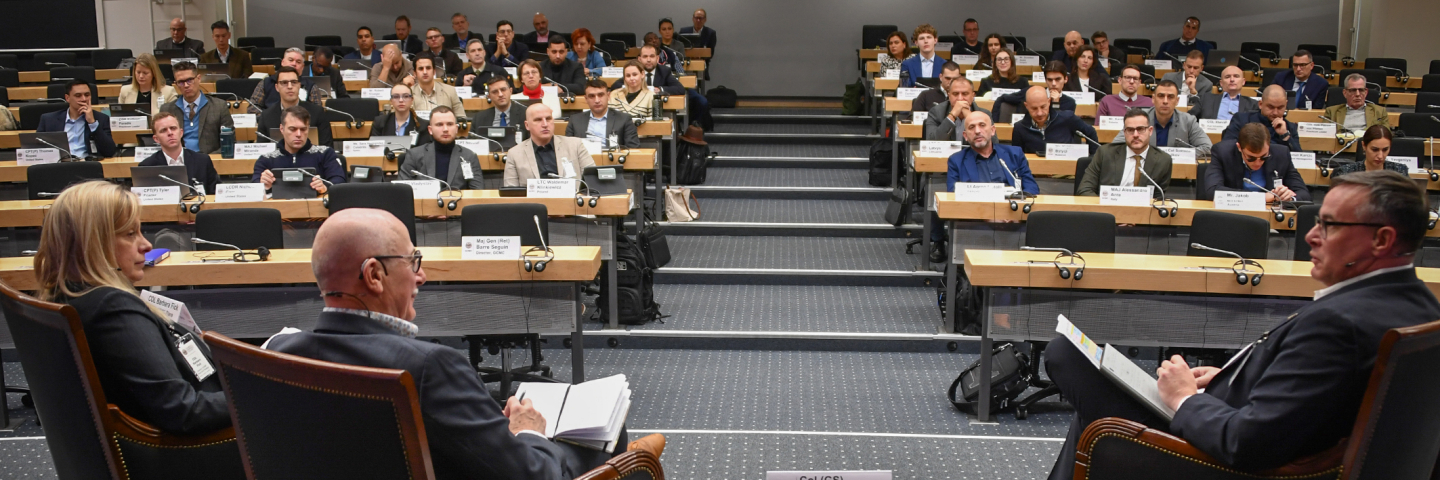 An expert panel debates in front of a full plenary audience.