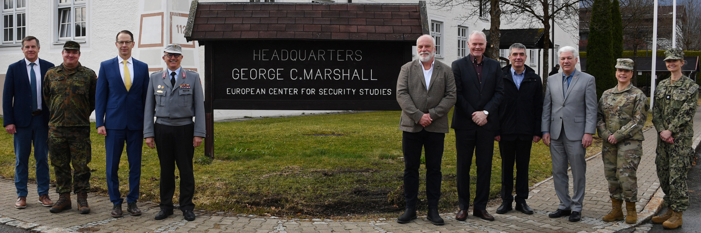 A group of civilian and military officials stand together outside the Marshall Center headquarters building in Garmisch-Partenkirchen, Germany.