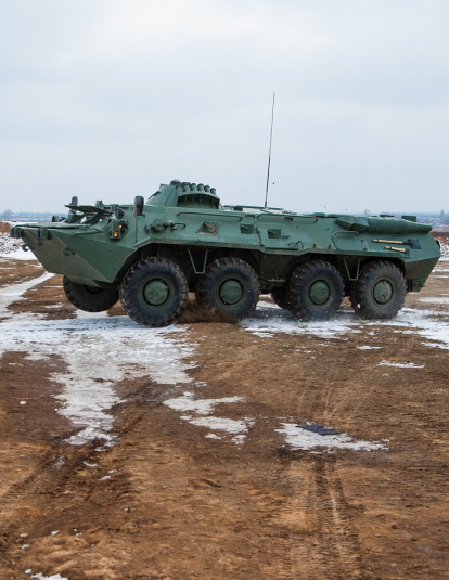 Photograph of a vehicle training for urban warfare in an abandoned field wiht empty apartment complexs in the background.