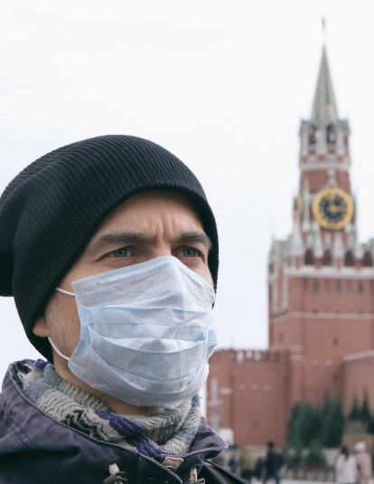 Portrait of adult man with medical protective mask on face with Kremlin and Red square on background.