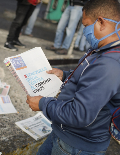 A man reads a newspaper whose headline reads "Venezuela united against the Coronavirus" outside the closed National Transport Terminal on March 17, 2020 in Caracas, Venezuela. 