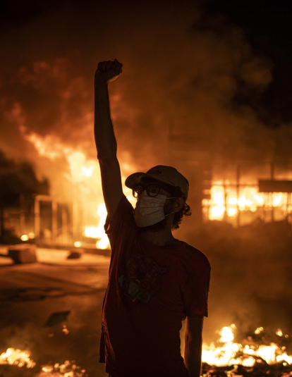  A protester wearing a face mask raises his fist in front of a burning building as large-scale protests resume on June 11, 2020 in Beirut, Lebanon.