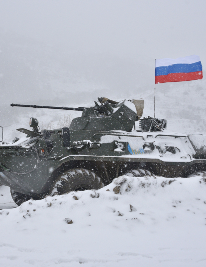 A Russian soldier of the peacekeeping force stand next to an Armored Personnel Carrier (APC) guard a checkpoint on the road to Lachin outside the town of Stepanakert on November 29, 2020, after six weeks of fighting between Armenia and Azerbaijan over the disputed Nagorno-Karabakh region.
