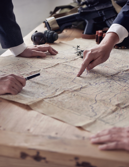 The hands of three men in suits discussing plans while looking at a map lying on a table