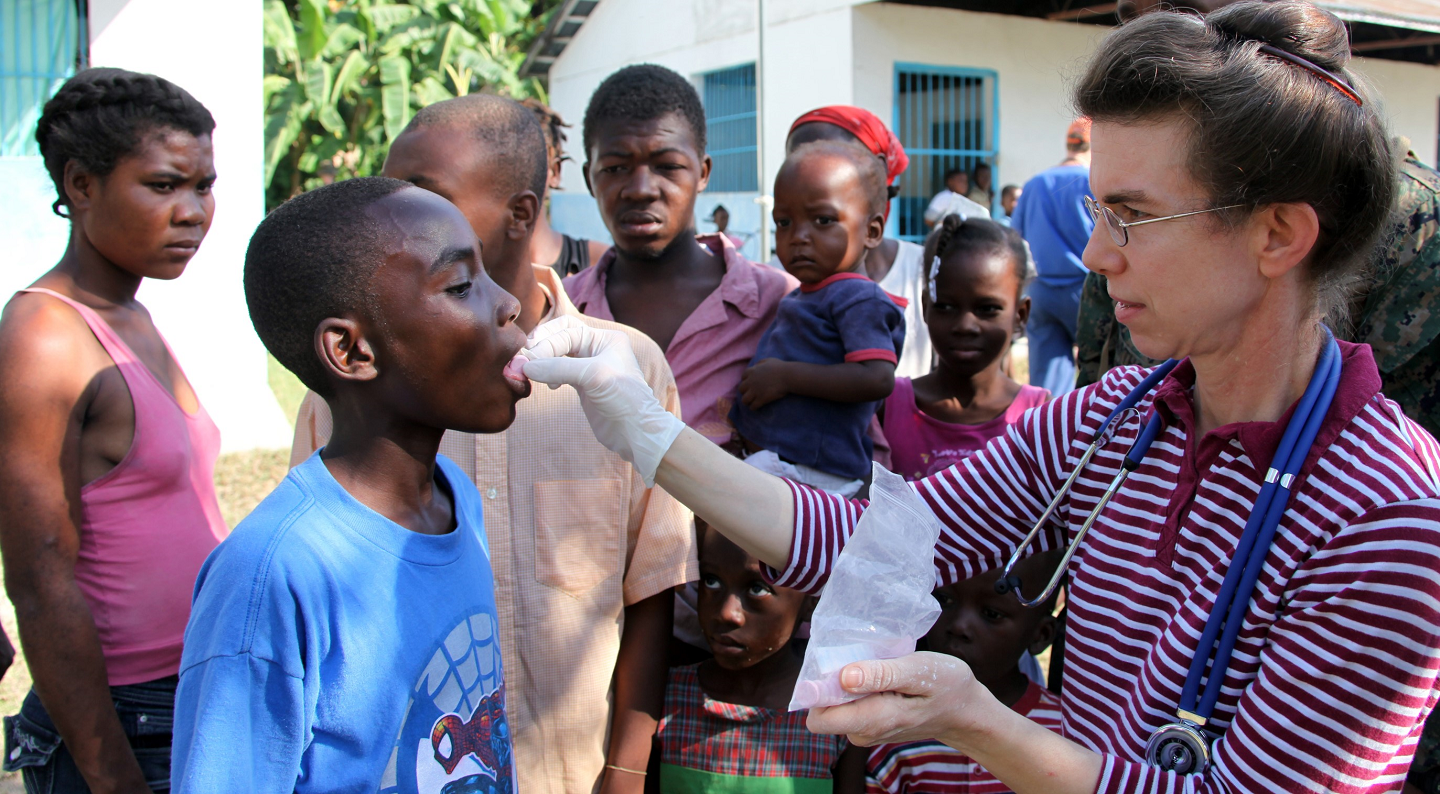 Photo of humanitarian aid worker administering medicine to a Haitian child