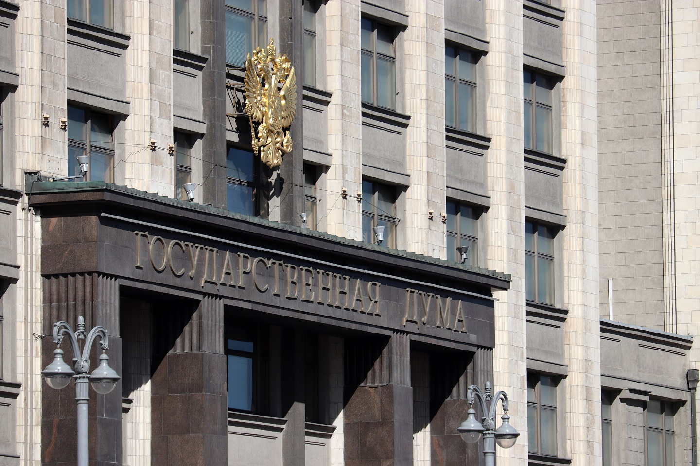 A photograph of the facade of Russian Parliament building in Moscow with emblem of Russia and inscription "State Duma". 