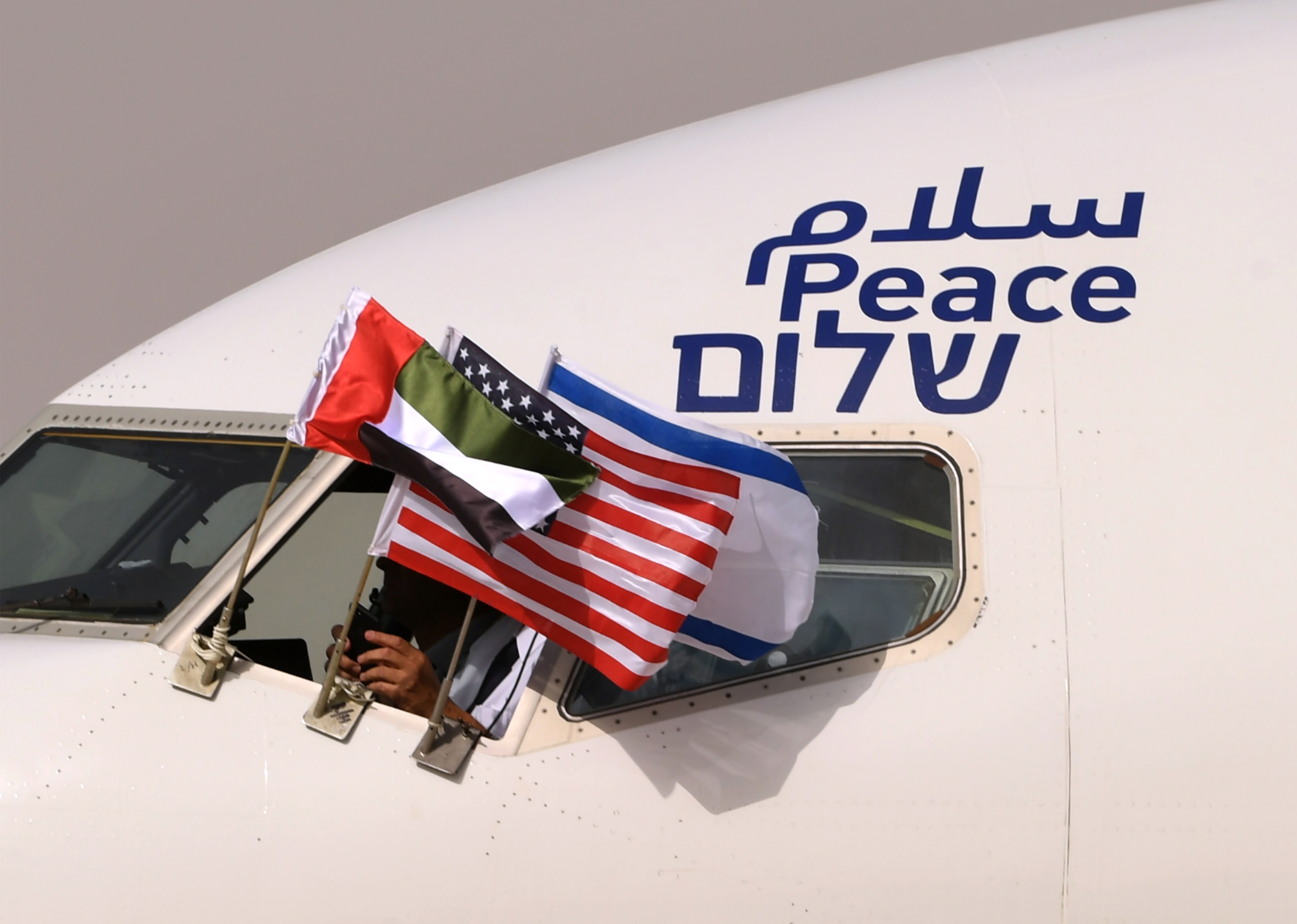 The Emirati, Israeli and US flags are picture attached to an air-plane of Israel's El Al, adorned with the word "peace" in Arabic, English and Hebrew, upon it's arrival at the Abu Dhabi airport in the first-ever commercial flight from Israel to the UAE, on August 31, 2020.