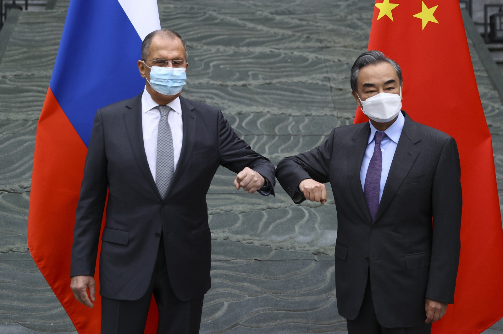 Chinese Foreign Minister Wang Yi and Russian Foreign Minister Sergei Lavrov (wearing masks) elbow bump ahead of their meeting in Beijing, China on March 22, 2021.