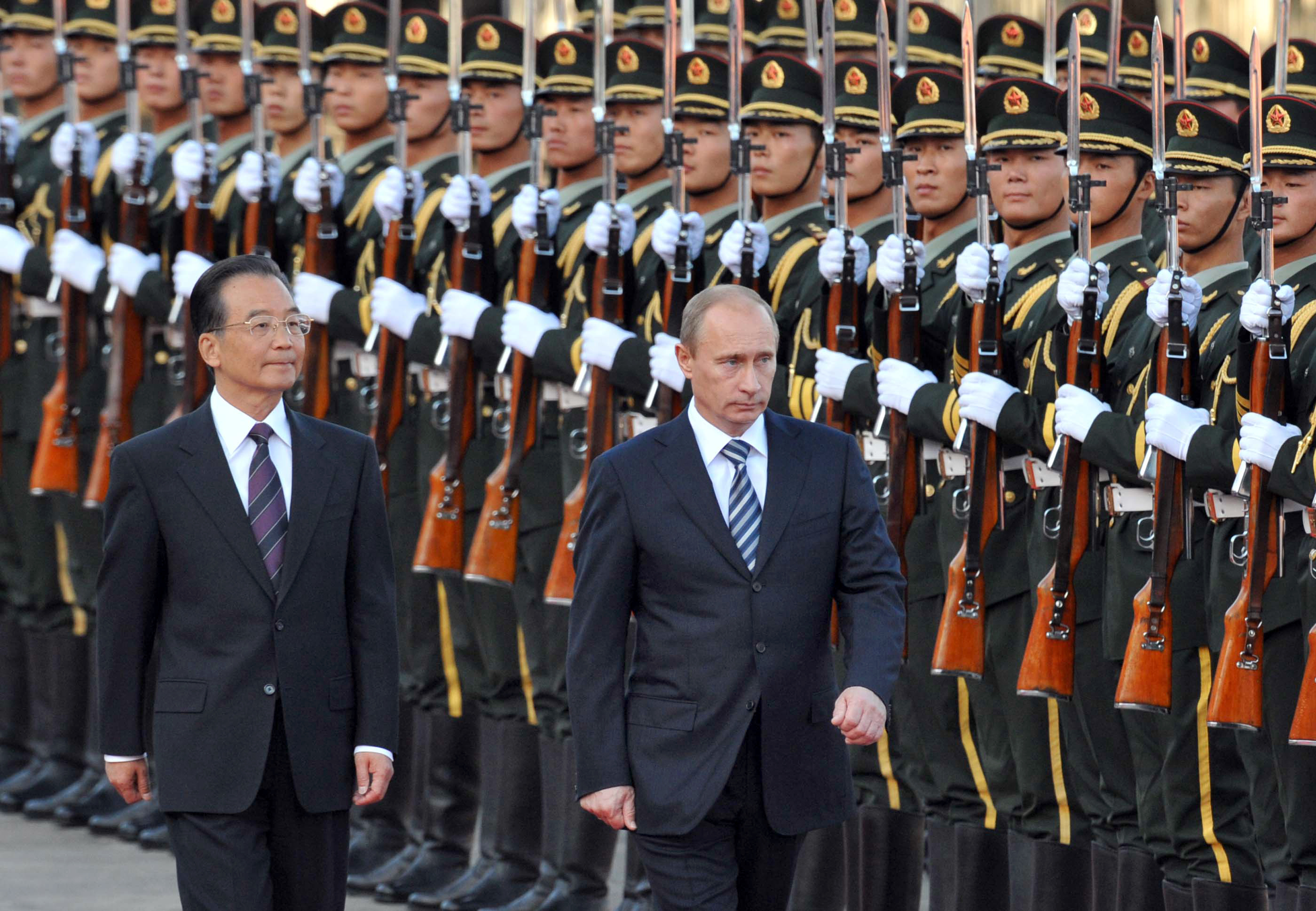 Russian Prime Minister Vladimir Putin walks with Chinese Premier Wen Jiabao past a military honour guard during a welcome ceremony at the Great Hall of the People in Beijing on October 13, 2009. 