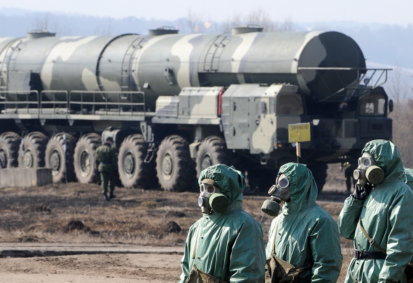 Russian soldiers wear chemical protection suits as they stand next to a military fueler on the base of a prime mover of Russian Topol intercontinental ballistic missile during a training session at the Serpukhov's military missile forces research institute some 100km outside Moscow on April 6, 2010.