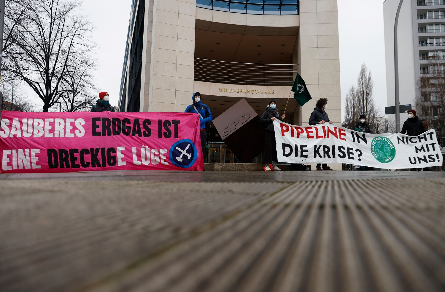 Activists of the "Fridays for Future" environmental and climate protection movement hold banners reading "Proper natural gas is a dirty lie" and "Pipeline into the crisis? Not with us!" as they demonstrate against the NordStream 2 gas pipeline and gas-related infrastructure on January 12, 2021 in front of the headquarters of the social democratic SPD party in Berlin.