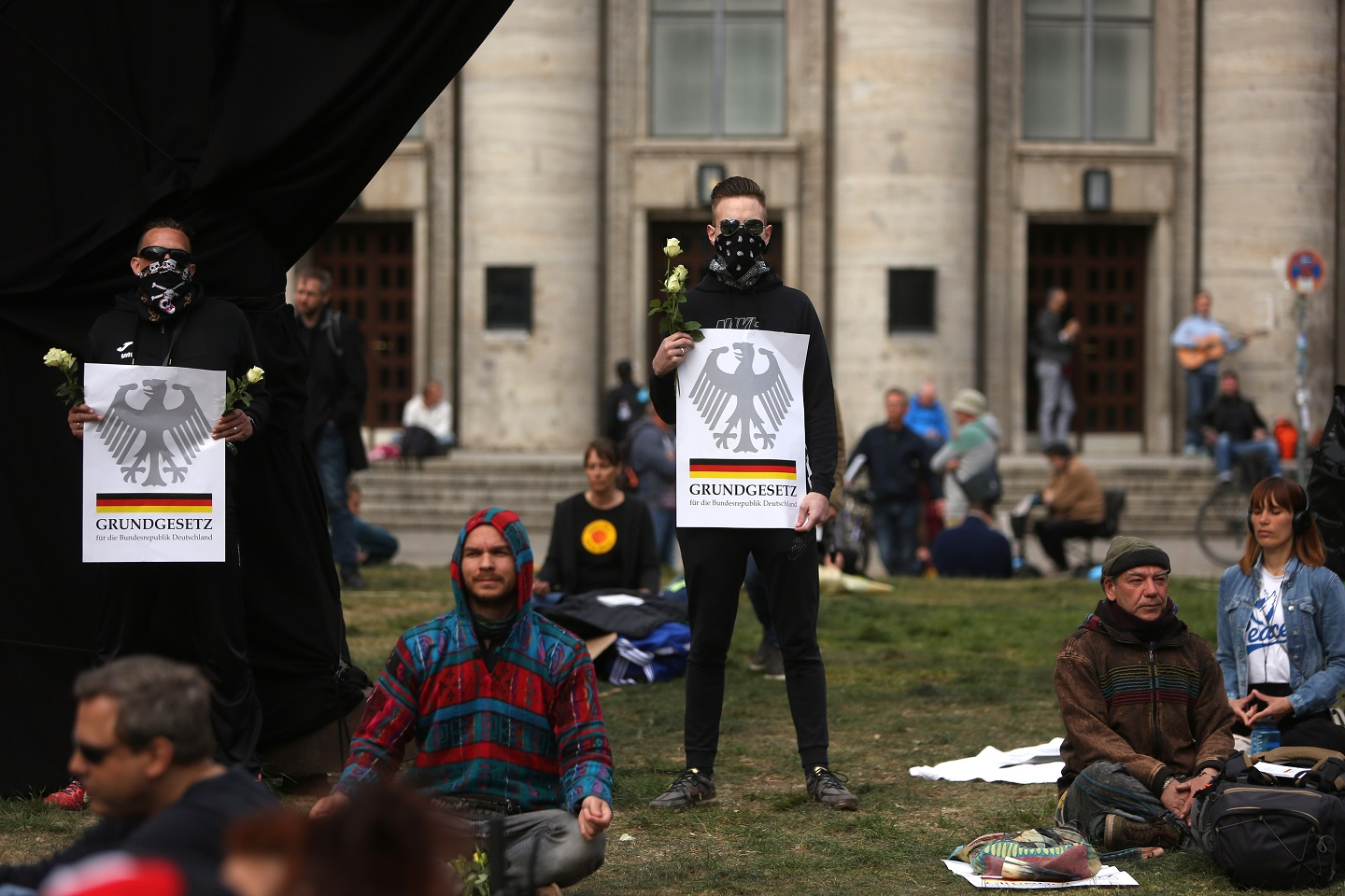 A photograph of Protesters holding signs referring to the Grundgesetz, or German constitution known as the basic law, as they demonstrate against restrictions on public life designed to stem the spread of the coronavirus, or COVID-19, on April 25, 2020 on Rosa Luxemburg Platz in Berlin, Germany.