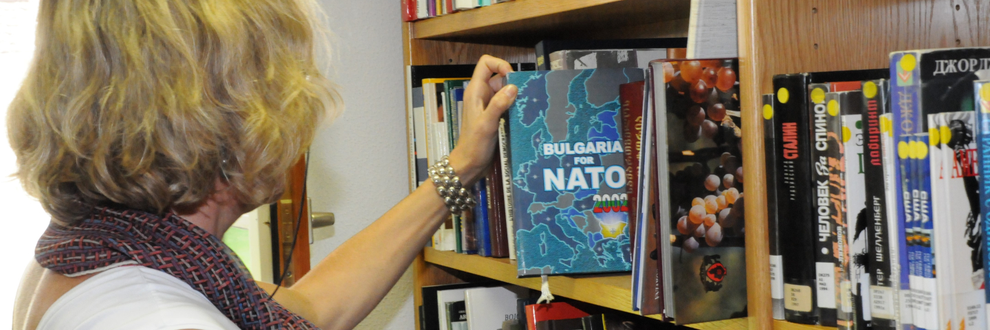 Woman looks at Bulgaria in NATO book at a library