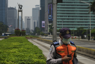 A policeman stands guard underneath The Welcome Monument in Jakartas nearly empty business district on March 30, 2020 in Jakarta, Indonesia.